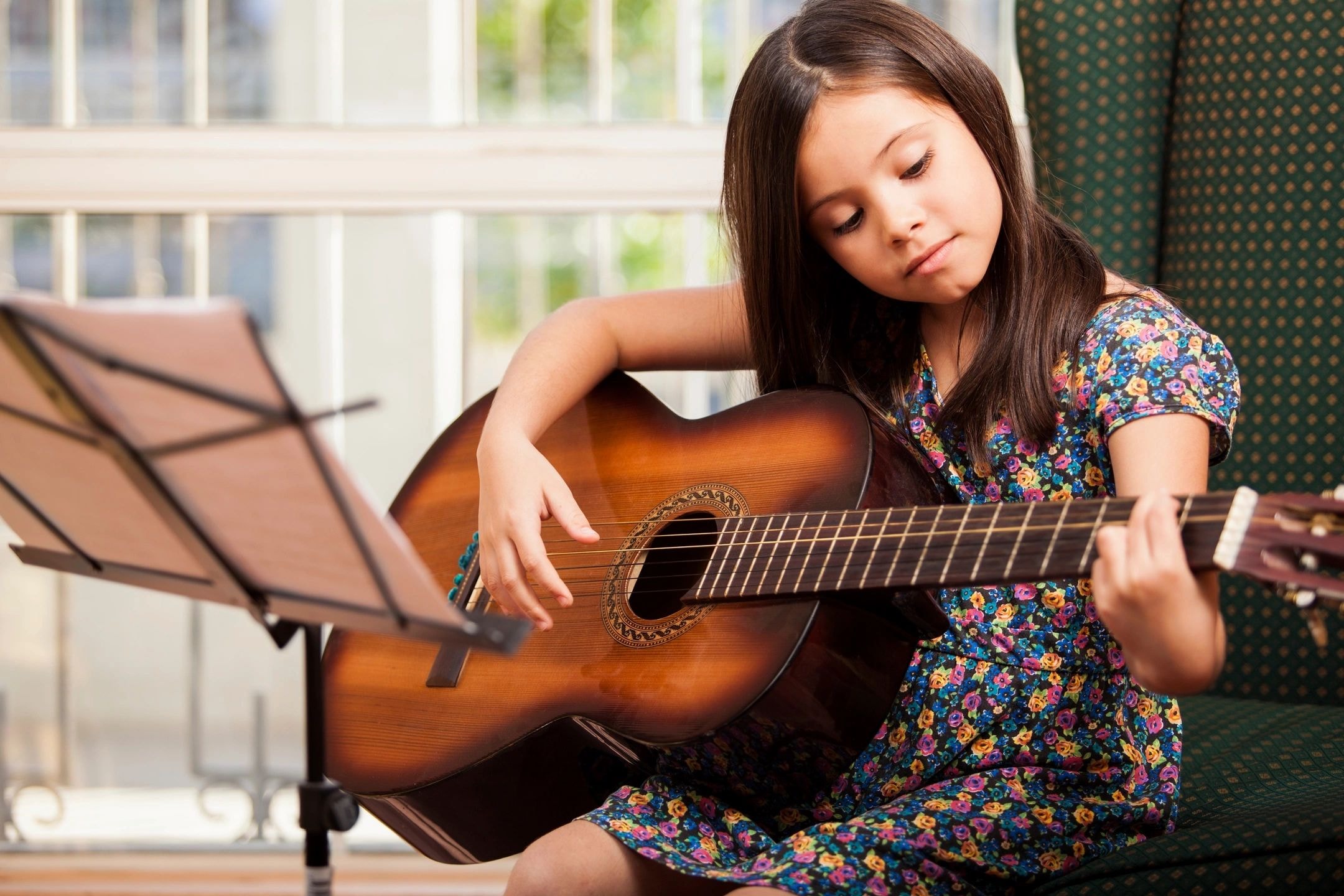 Girl playing acoustic guitar reading sheet music